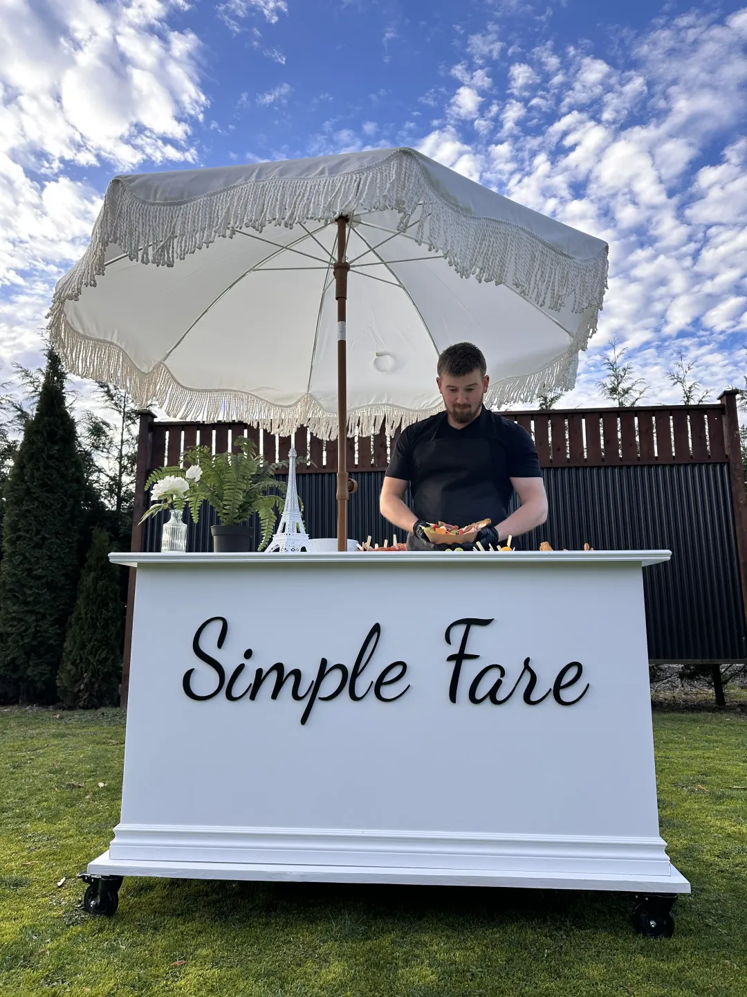 Simple Fare charcuterie cart with a fringe umbrella set up for a Mission event